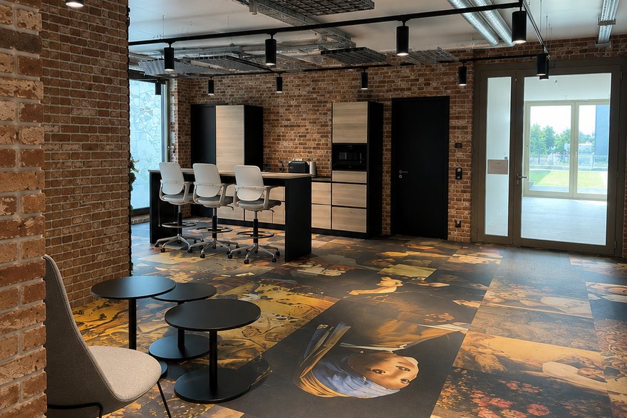 Ausgebaute Bürofläche mit Sichtziegelwänden, offen geführter Deckentechnik, Teeküche mit Barhockern und Loungebereich.