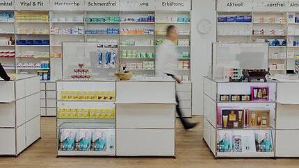 Verkaufsraum einer Apotheke mit weißen Modulregalen, Sichtwahl an der Wand und Freiwahl-Inseln.